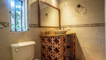 A bathroom with a toilet, a sink with a mirror above it, and a decorative tile border.