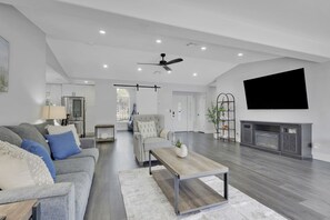 Ein geräumiges Wohnzimmer mit Sofa, Sessel, Couchtisch und Kamin.