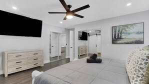 A bedroom with a bed, a dresser, a ceiling fan, a TV, and a painting. - Spacious 4BR Home w/ Heated Pool & Pickleball Court on 5-Acre Estate (Naples)