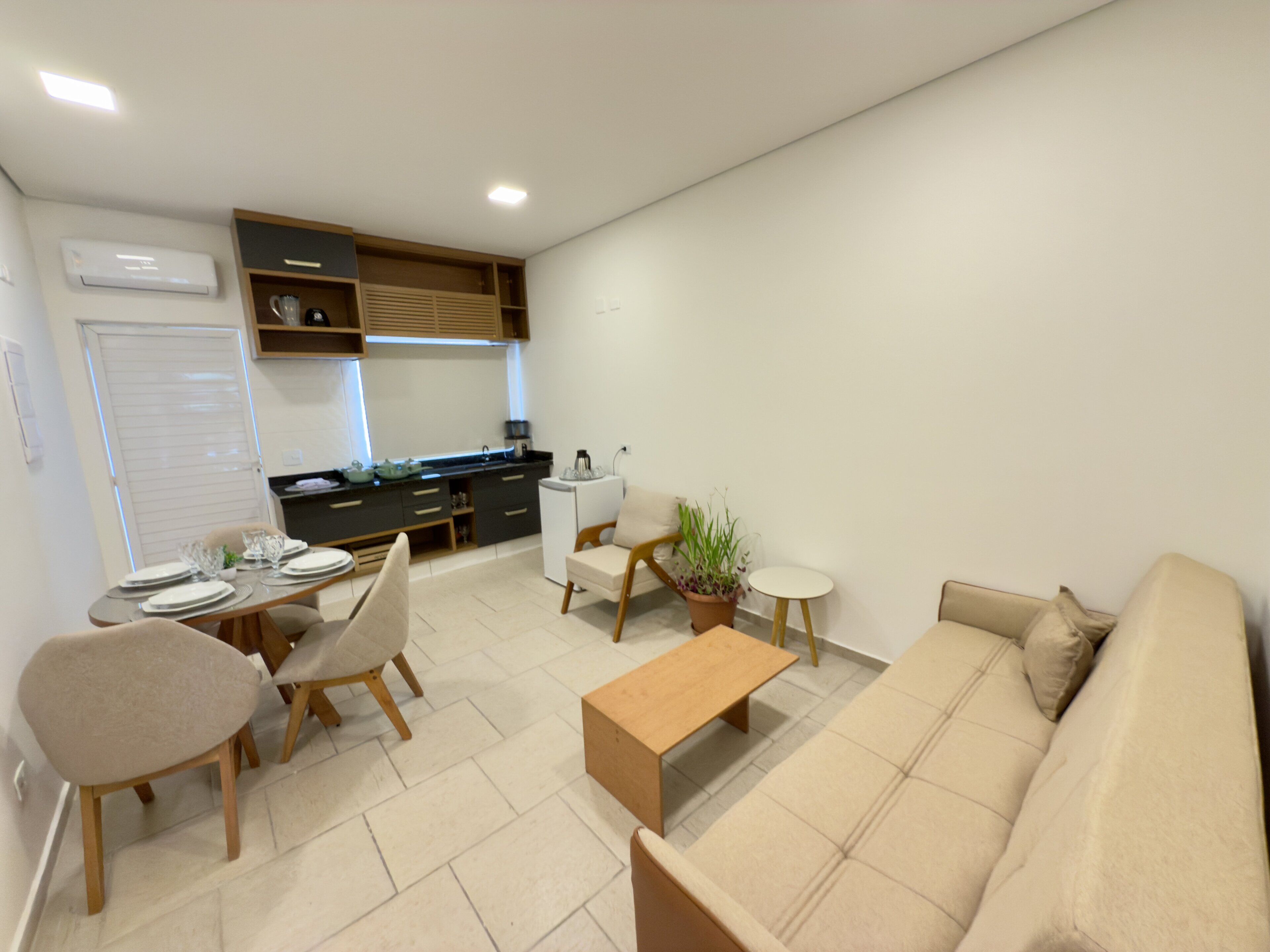 A modern living room with a sofa, coffee table, and dining area with chairs and a table set for four.