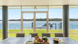 Un espace extérieur abrité où l’on peut prendre ses repas, avec vue sur un lac et un yacht.