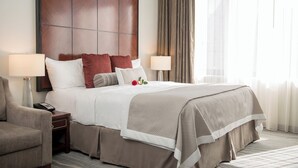 Une chambre d’hôtel avec un grand lit, deux tables de chevet, une chaise et une tête de lit en bois.