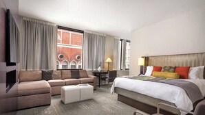 Une chambre d’hôtel avec un canapé, un lit, une télévision et une fenêtre avec des rideaux.