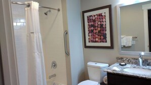 Une salle de bain équipée d’une douche, de toilettes, d’un lavabo et d’une œuvre d’art florale encadrée au mur.