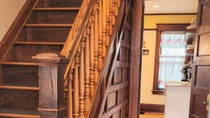 A wooden staircase with a patterned rug leading to a kitchen area.
