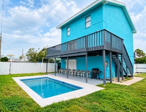 A two-story building with a pool and outdoor seating area. - Four Bedroom House Steps From the Beach (South Padre Island)