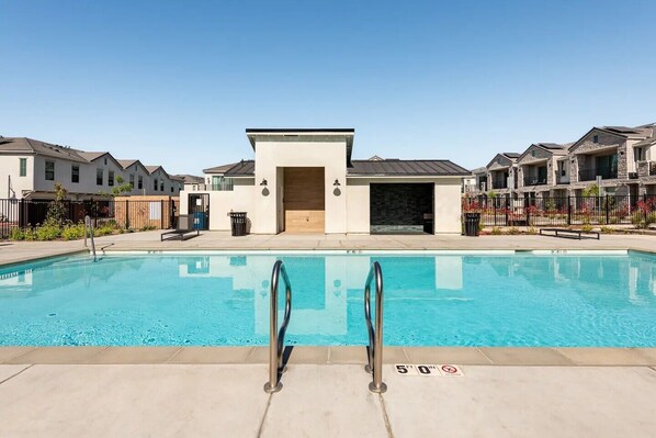 A swimming pool with a clear blue water, surrounded by a paved deck. There are two metal ladders on the pool's edge. - Clovis Retreat - Modern 2BR Near Parks, Pool (Clovis)