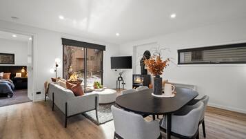 A modern living room with a fireplace, a dining table, and comfortable seating.