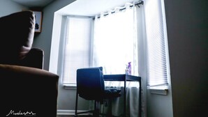 Ein Zimmer mit Fenster, Stuhl und Tisch.