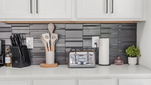 A kitchen with white cabinets, a toaster, a knife block, a bottle of olive oil, and a plant. - 1 King Loft W/Parking + Laundry I Oak Lawn + DT (Dallas)