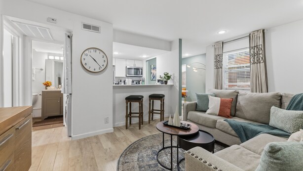Een moderne woonkamer met een bank, salontafel en een eethoek met krukken.