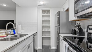 Een moderne keuken met witte kasten, een roestvrijstalen koelkast en een inbouwoven.