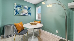 Een eetruimte met blauwgroene wanden, een witte tafel en moderne stoelen.