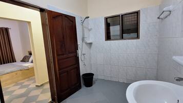 Ein Badezimmer mit Dusche, Waschbecken und Fenster.