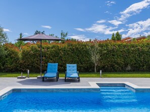 A swimming pool with two blue lounge chairs and a large umbrella. - Istria Queen by Interhome (Labin)