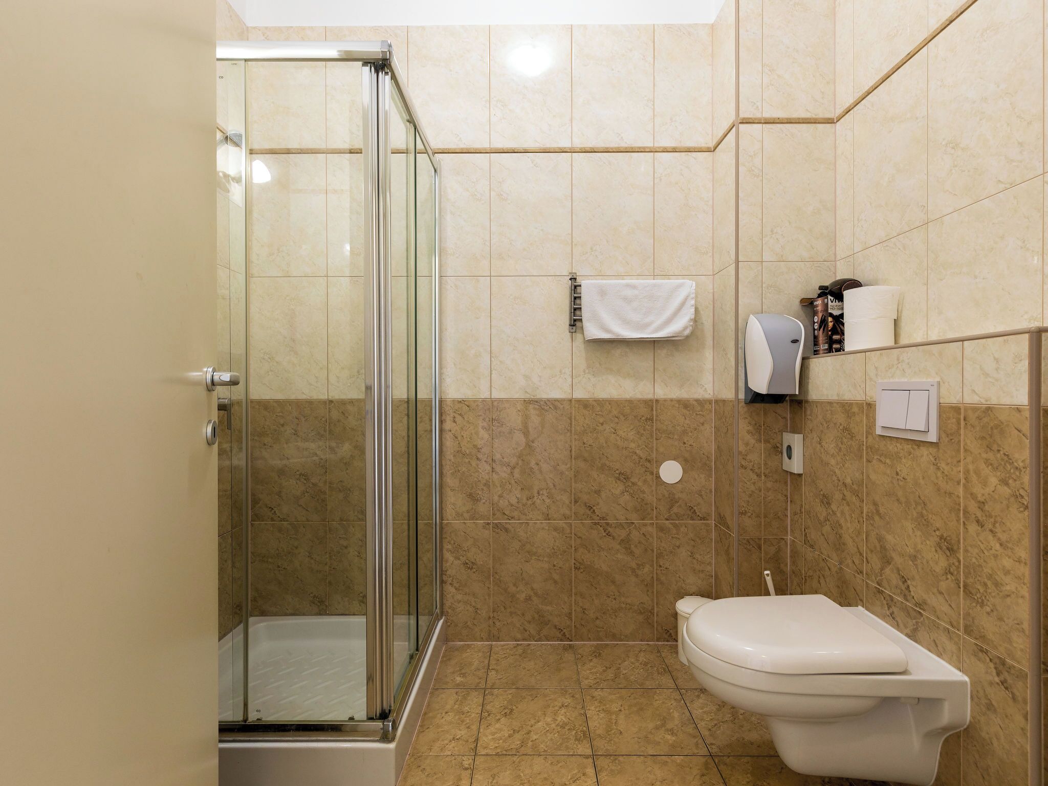 A bathroom with a glass shower enclosure, a toilet, and a towel rack.