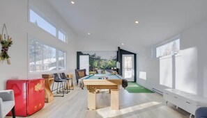 Ein moderner Raum mit Pooltisch, Sitzgelegenheit und großen Fenstern.