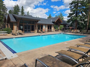 A swimming pool with lounge chairs and a building with large windows.