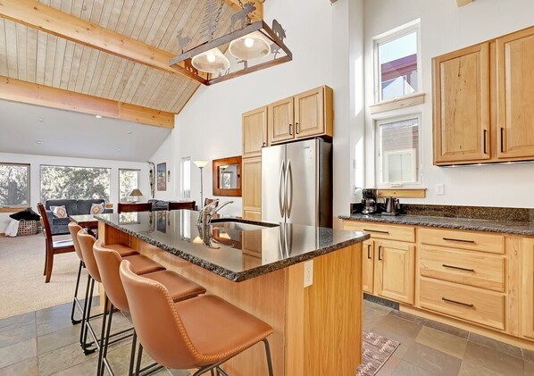 A modern kitchen with a central island, wooden cabinets, and a stainless steel refrigerator.