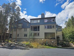 A multi-story residential building with a stone foundation, multiple windows, and a balcony.