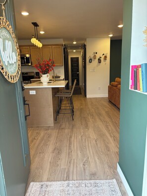 Una cocina moderna con suelo de madera, una isla central y un comedor con banco.
