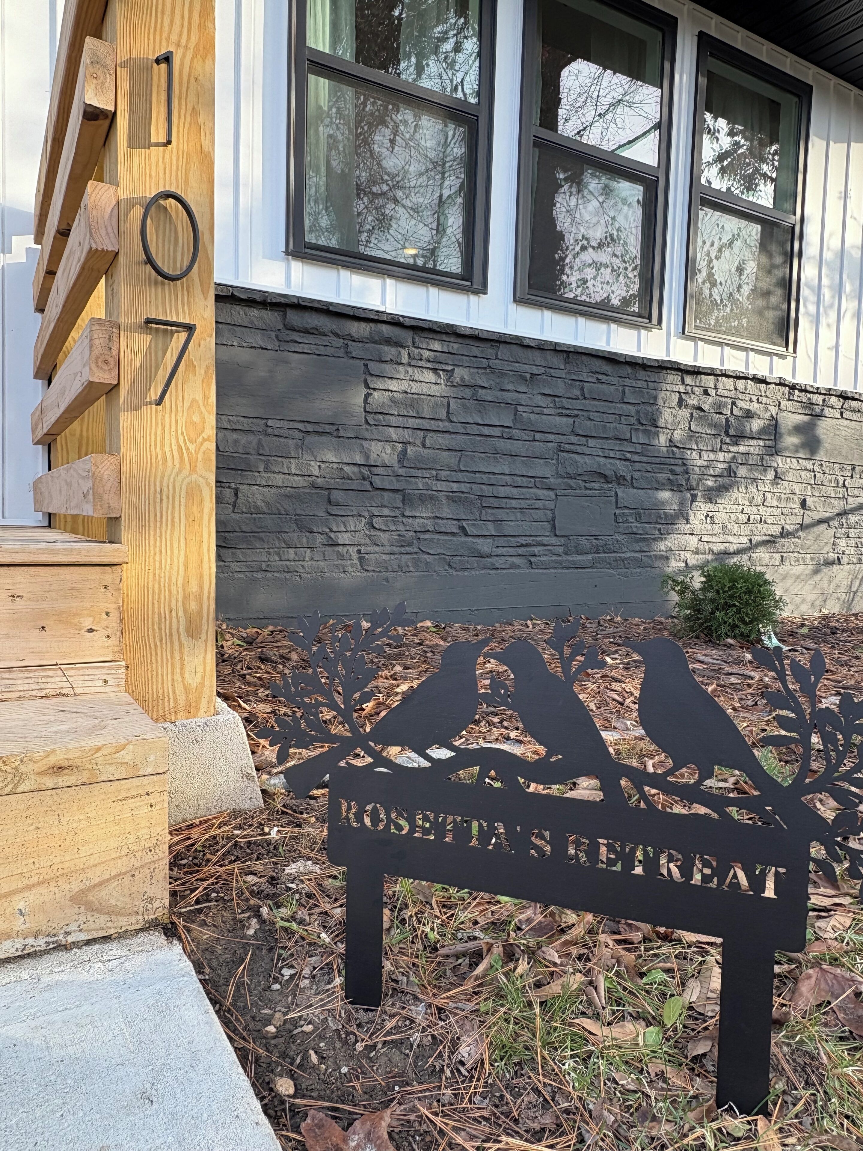 A wooden mailbox with the number 107, a stone wall, and a sign for Rosetta's Retreat.