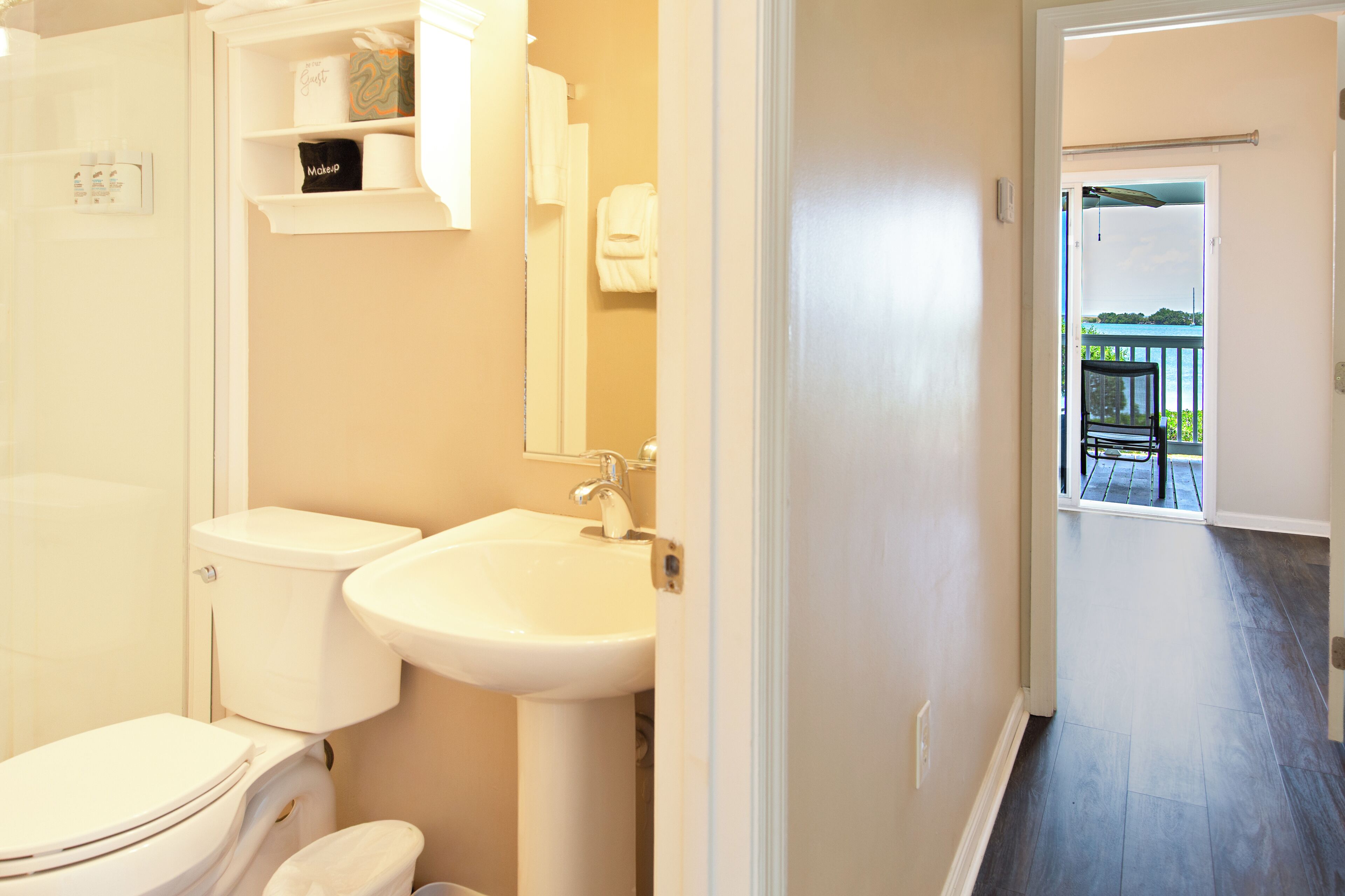 Une salle de bain équipée de toilettes, d’un lavabo et d’une étagère où sont rangés les articles de toilette.