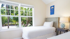 Une chambre avec une grande fenêtre, un lit, une table de chevet et une lampe fixée au mur.