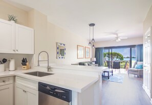Een moderne keuken met een vaatwasser, een eethoek met uitzicht en een woonkamer met plafondventilator.