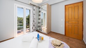 Una camera d'albergo con un letto, una finestra con tende, una porta in legno e vista sull'esterno.