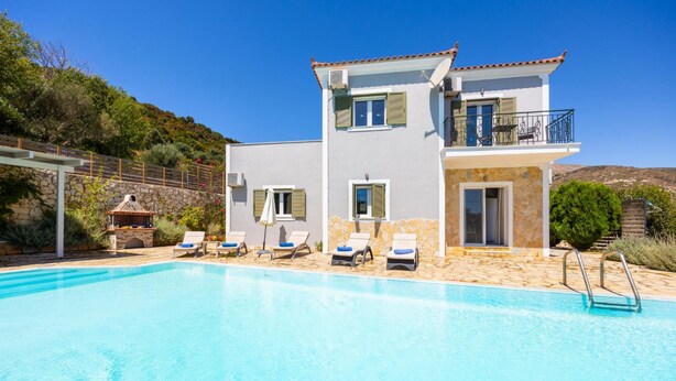 Una casa a due piani con piscina, area relax esterna e un muro in pietra.