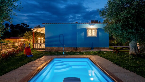 Une piscine rectangulaire à l’eau d’un bleu limpide, entourée d’un chemin pavé de pierres.