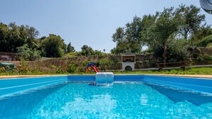 A swimming pool with a slide, surrounded by greenery and a stone wall. - peaceful Kefalonia villa with private pool (Spartia)