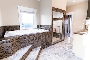 Un baño moderno con una bañera grande, cabina de ducha con vidrio y una ventana que proporciona luz natural.