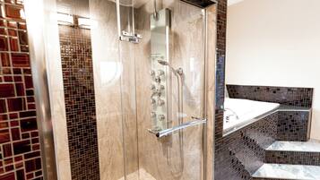 A modern bathroom with a glass-enclosed shower, a marble-tiled wall, and a built-in sink with a glass ledge.