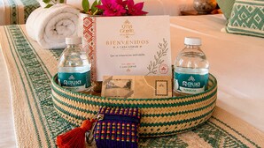 A hotel room with a bed, pillows, a welcome card, and two water bottles. - Hotel boutique Casa Gopar (Ocotlán de Morelos)