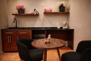 A compact kitchen with dark wood cabinets, a black countertop, and a round wooden table with a decorative item. - Hotel boutique Casa Gopar (Ocotlán de Morelos)