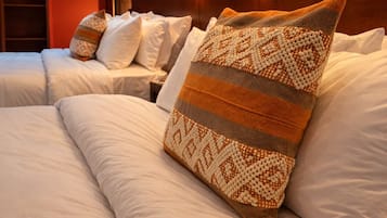 A hotel room with a brick-patterned wall, two beds with white bedding, and two wall-mounted light fixtures.