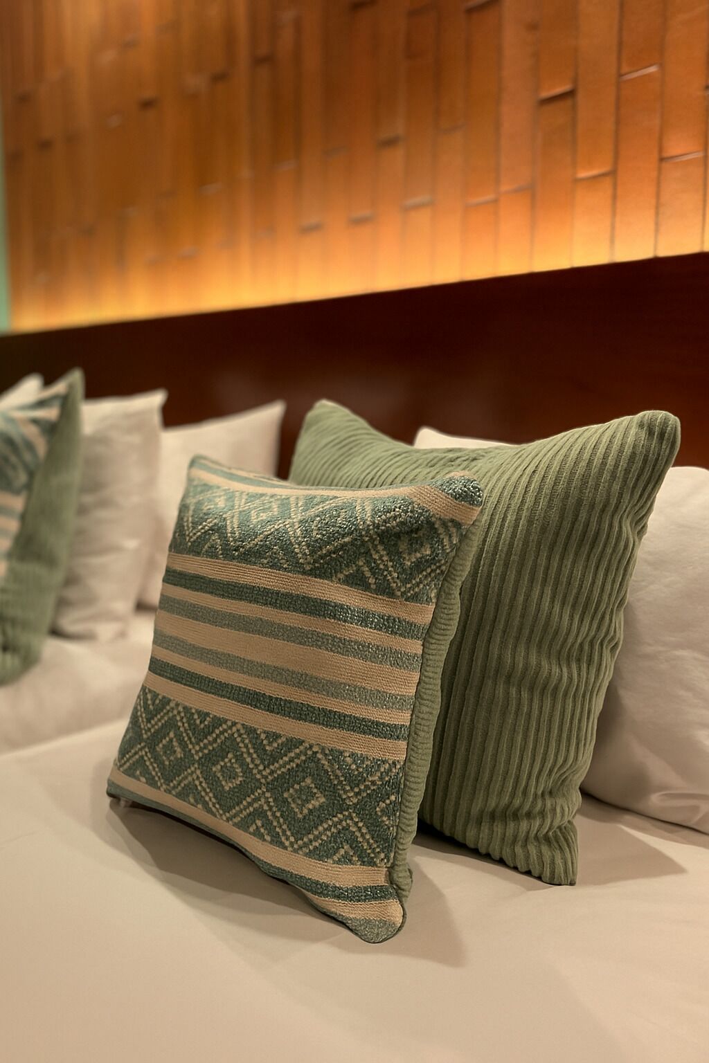 A bed with multiple pillows, including a patterned one and a ribbed one.