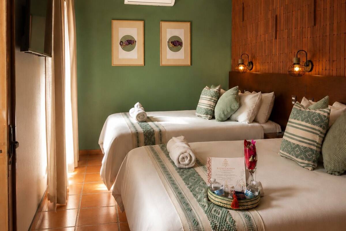Camera d'albergo con due letti, un pannello di legno, una TV a schermo piatto e un condizionatore d'aria a muro.