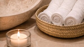 A bathroom with a stone sink, a woven basket of rolled towels, and a lit candle. - Hotel boutique Casa Gopar (Ocotlán de Morelos)