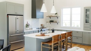 A modern kitchen with a central island, stainless steel appliances, and wooden chairs. - Luxury Ranch Near Palo Pinto Park with 10 Beds (Strawn)