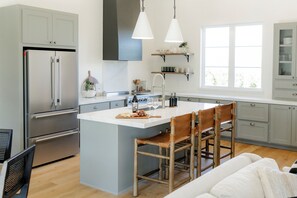 Una cocina moderna con una isla central, electrodomésticos de acero inoxidable y sillas de madera.