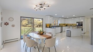Una cocina moderna con armarios blancos, una isla central y un comedor con mesa y sillas.