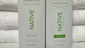 Two bottles of Native body wash and shampoo on a shelf with folded towels in the background. - Bobbi's on the Hill (Waynesville)