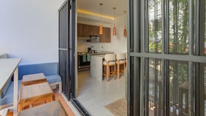 A modern kitchen with a microwave, wooden cabinets, and a bar area with stools. - Rooftop Pool & Ocean Views Malecón, 5 de Diciembre (Puerto Vallarta)
