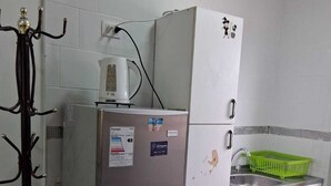 Uma cozinha compacta com geladeira, cafeteira e pia.