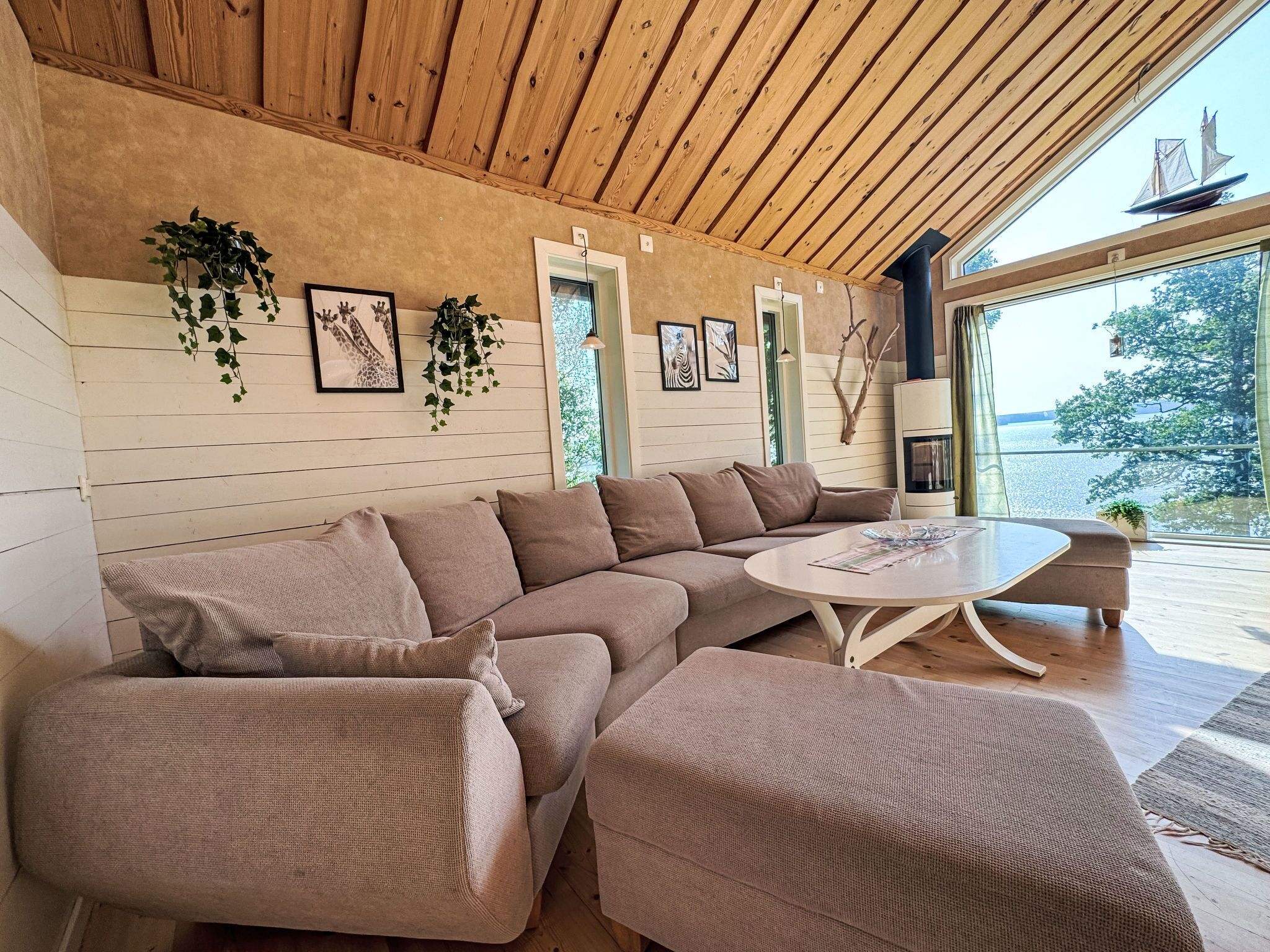 Uma sala de estar moderna com teto de madeira, uma janela grande e vista para o exterior.