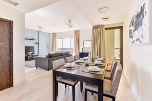 A modern dining area with a dark wooden table set for six, surrounded by six chairs. - Luxury 3BR JBR · Shams · Free 5* Beach Resorts Access! (Dubai)