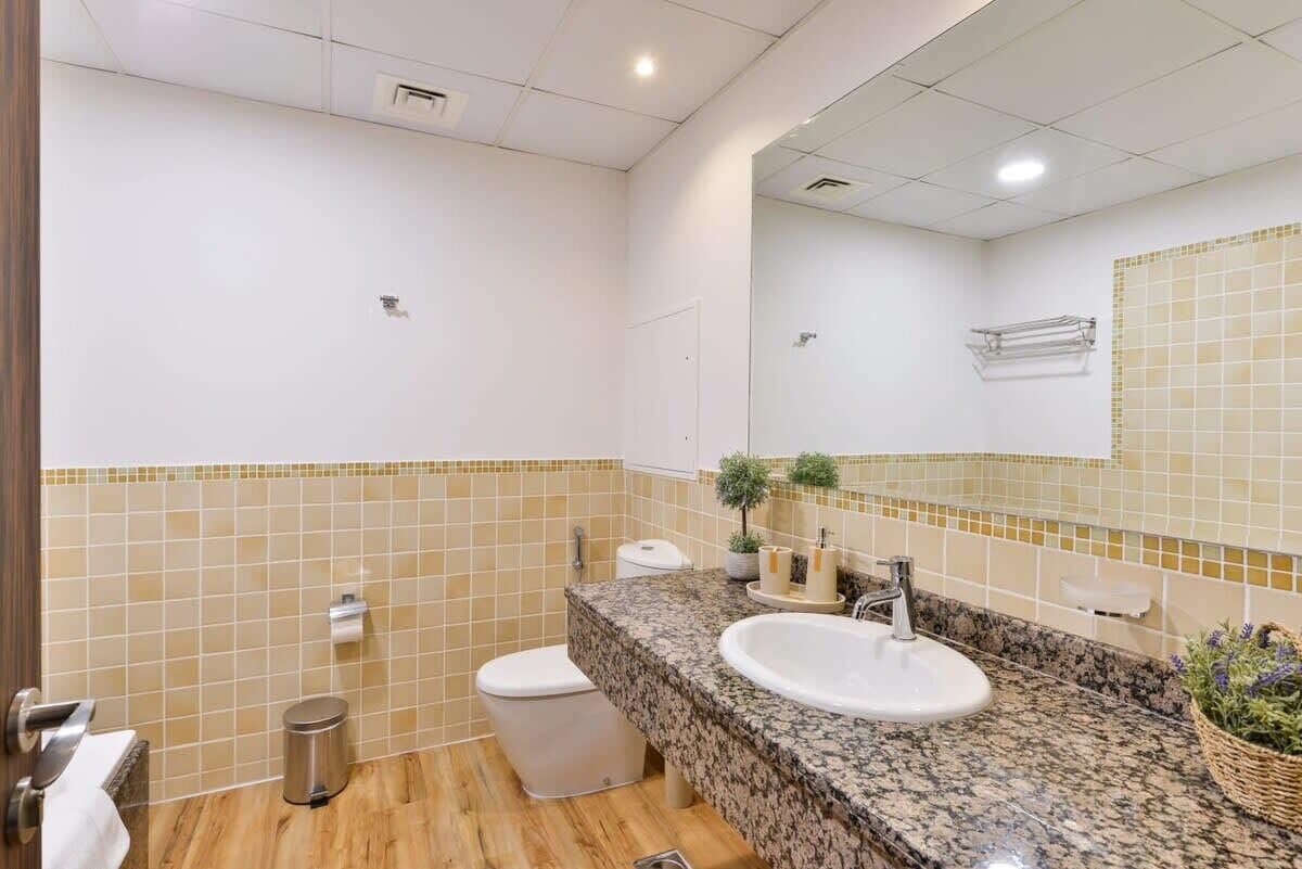 A bathroom with a marble sink, a toilet, and a mirror.